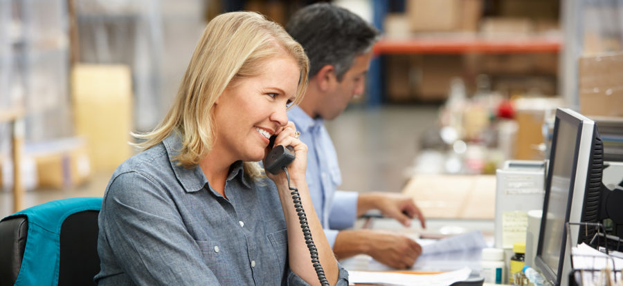 Woman in warehouse talking on phone to staffing agency