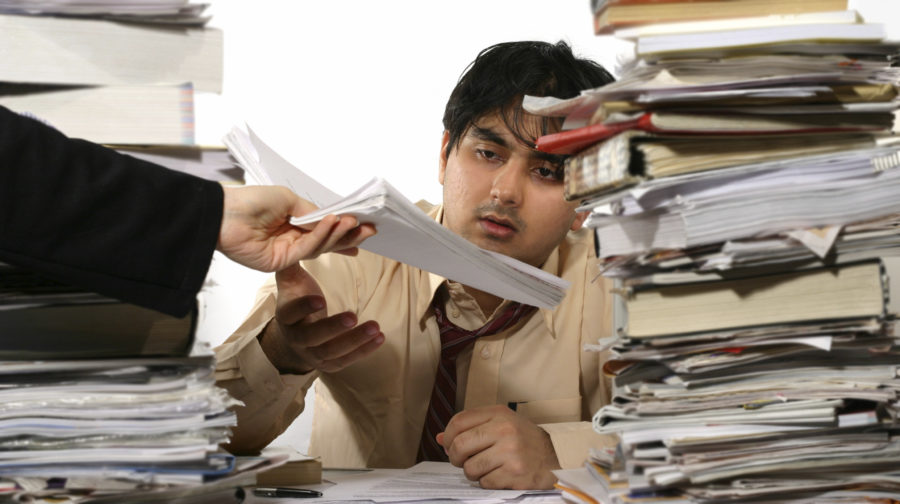 Overwhelmed man with mountain of work